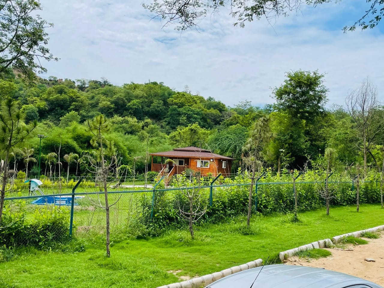 Lush green perimeter fence, swimming pool and foothills at Village Bardar